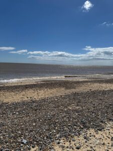 Pebbles, sand, surf, open water, and sky on the Kessingland coast.